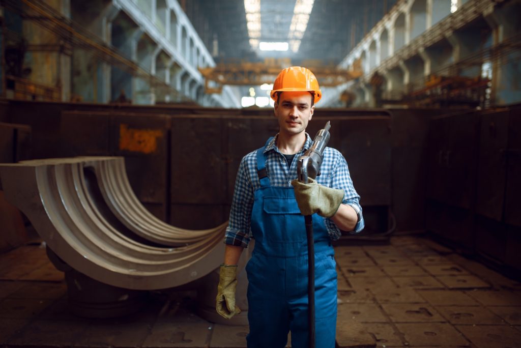 Male worker holds pneumatic jackhammer on factory